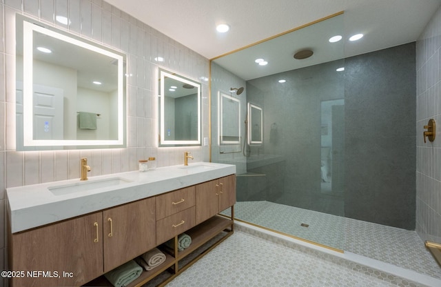 bathroom with double vanity, tile walls, walk in shower, and a sink