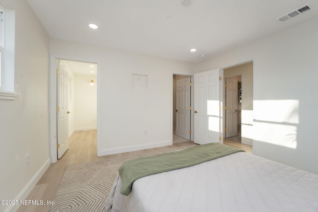 bedroom with light wood-style floors, recessed lighting, visible vents, and baseboards