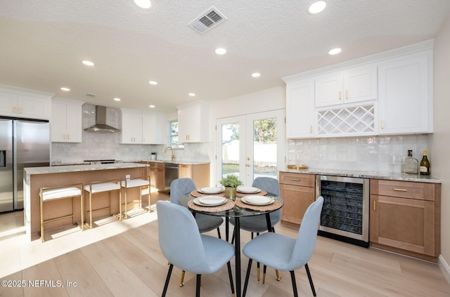 dining area with visible vents, wine cooler, french doors, a bar, and light wood-style floors