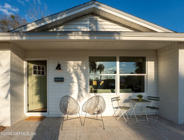 entrance to property featuring brick siding and a patio