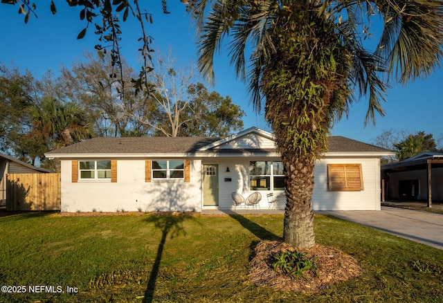 single story home with concrete driveway, a front lawn, and fence