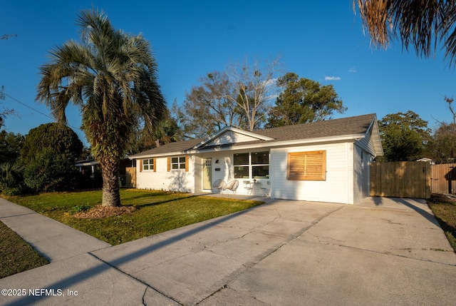 single story home featuring driveway, a front lawn, fence, and a gate