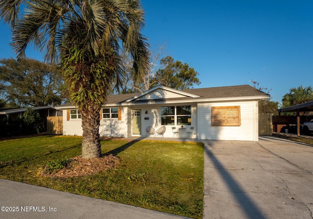 ranch-style house with a shingled roof, concrete driveway, fence, and a front lawn