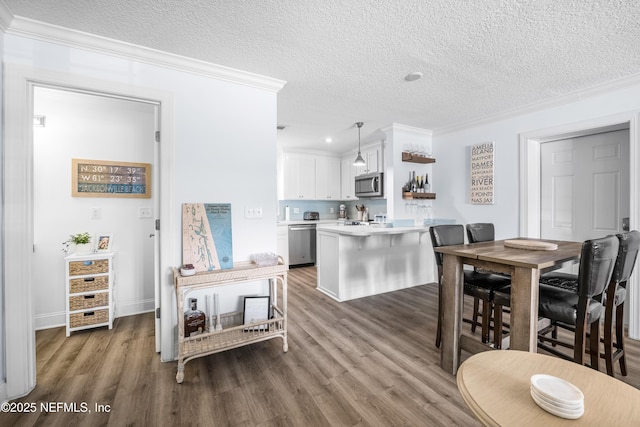 kitchen with pendant lighting, stainless steel appliances, light countertops, white cabinetry, and a peninsula