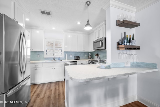 kitchen with open shelves, appliances with stainless steel finishes, white cabinets, a sink, and a peninsula