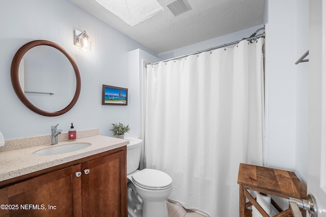 full bath with a textured ceiling, toilet, a skylight, vanity, and visible vents