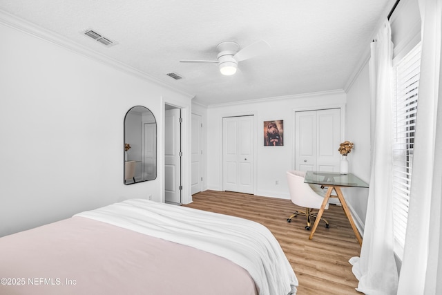 bedroom with visible vents, ornamental molding, ceiling fan, a textured ceiling, and wood finished floors