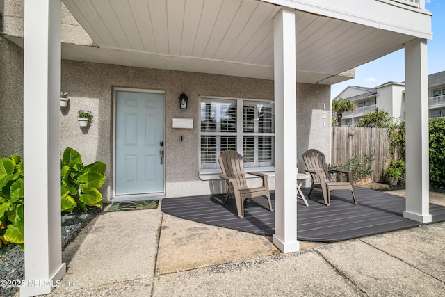 view of exterior entry with fence and stucco siding