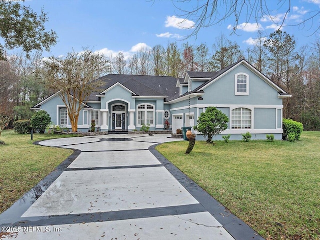 view of front of house with a garage, a front yard, concrete driveway, and stucco siding