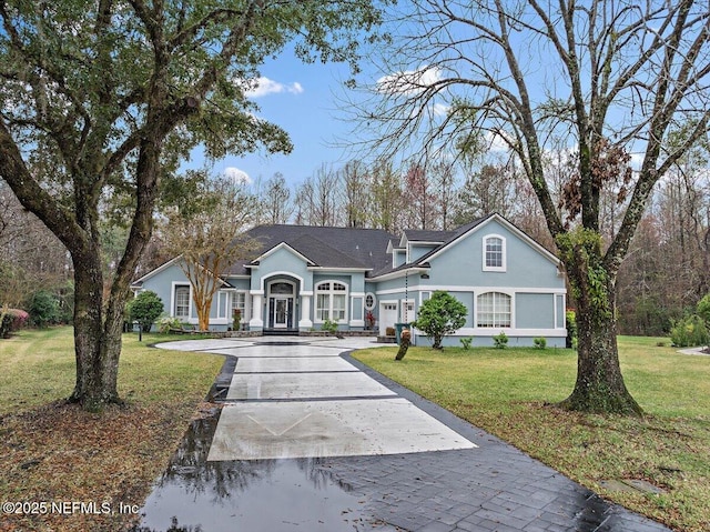 view of front of home with a garage, concrete driveway, a front lawn, and stucco siding