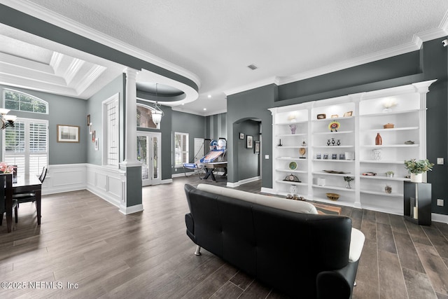 living room featuring dark wood-type flooring, a wainscoted wall, a notable chandelier, and ornamental molding