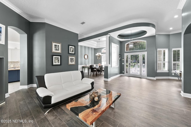 living room with ornamental molding, arched walkways, dark wood-style flooring, and baseboards