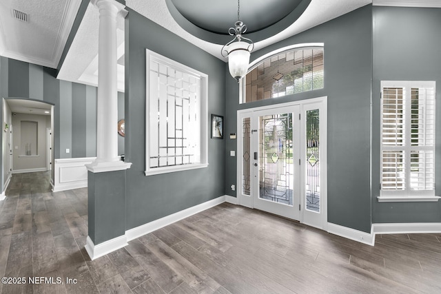 foyer entrance with decorative columns, baseboards, a raised ceiling, and wood finished floors