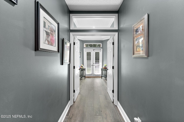 hall with baseboards, wood finished floors, and french doors