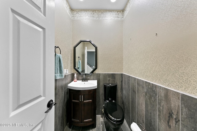 half bath with a wainscoted wall and vanity