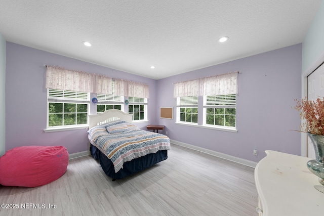 bedroom with multiple windows, light wood finished floors, and baseboards