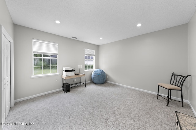 living area featuring recessed lighting, light colored carpet, a textured ceiling, and baseboards