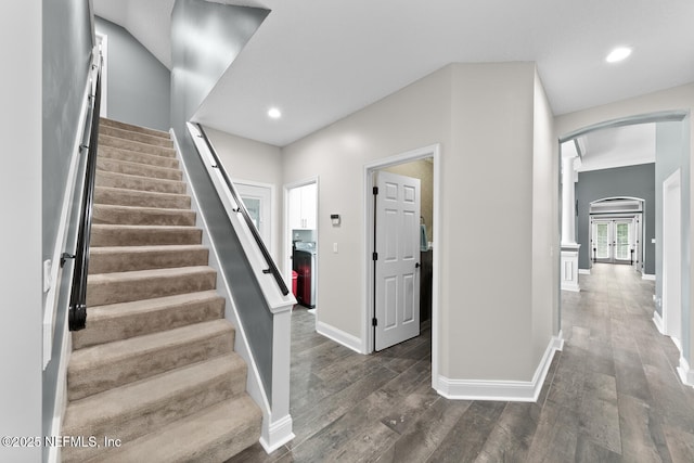 stairway with recessed lighting, arched walkways, baseboards, and wood finished floors