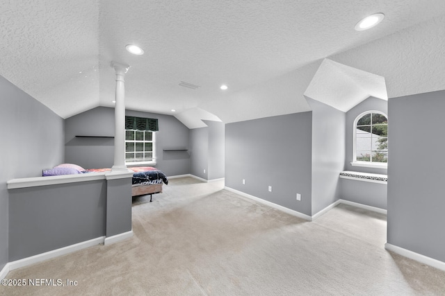 bedroom with lofted ceiling, multiple windows, decorative columns, and baseboards