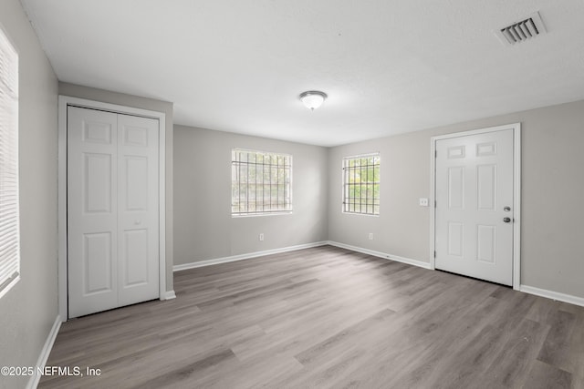 unfurnished bedroom with a closet, visible vents, light wood-style flooring, and baseboards