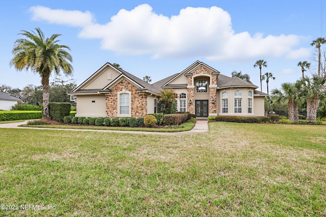 view of front of property with a front yard, stone siding, and stucco siding