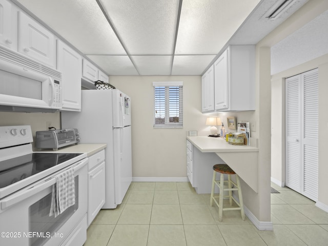 kitchen featuring light tile patterned floors, white appliances, light countertops, and white cabinetry