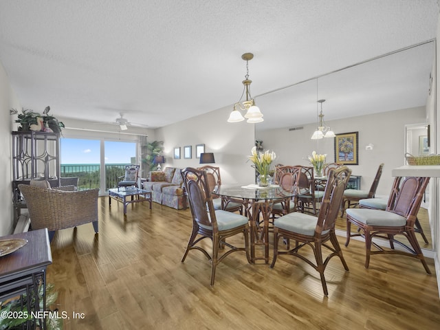 dining area with ceiling fan, visible vents, light wood finished floors, and a textured ceiling