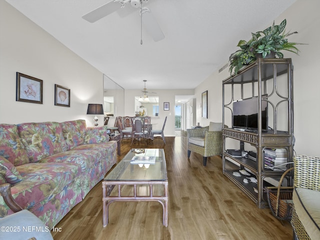 living area with ceiling fan, visible vents, and wood finished floors