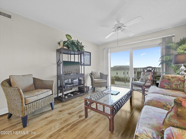 living area featuring baseboards, visible vents, light wood-type flooring, and ceiling fan