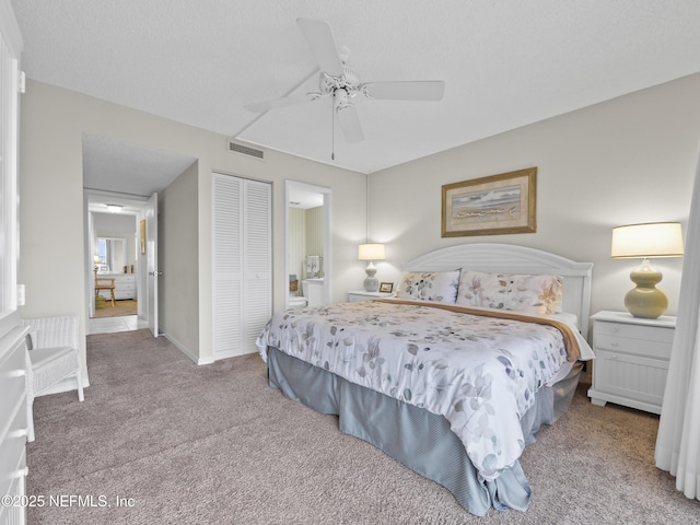carpeted bedroom featuring visible vents, a closet, ensuite bath, and a ceiling fan