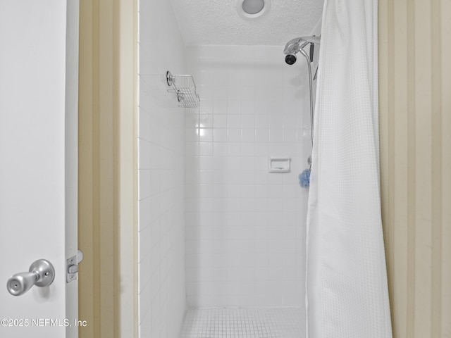 full bath featuring a tile shower and a textured ceiling