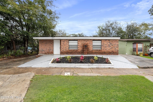 single story home with concrete driveway, brick siding, and a front yard