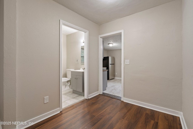 interior space with a sink, a textured ceiling, baseboards, and wood finished floors