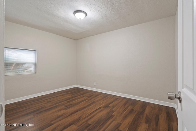 unfurnished room with dark wood-type flooring, a textured ceiling, and baseboards