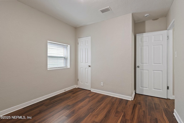 unfurnished bedroom featuring baseboards, visible vents, and dark wood-style flooring