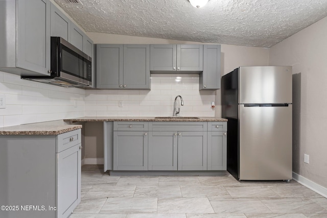 kitchen with appliances with stainless steel finishes, gray cabinets, and a sink