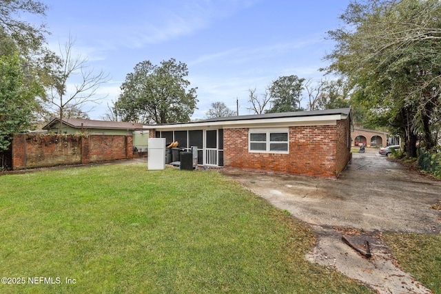 rear view of house featuring a yard, brick siding, central AC unit, and fence