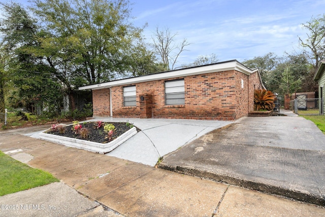 view of front of house featuring concrete driveway, brick siding, and fence