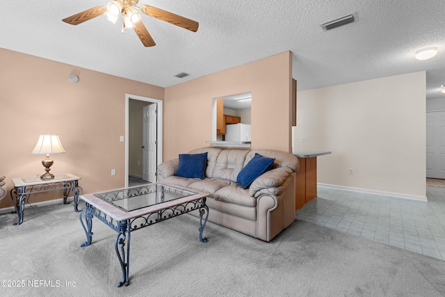 living area featuring carpet floors, visible vents, and a textured ceiling