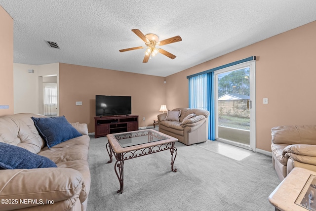 living area with baseboards, visible vents, a ceiling fan, a textured ceiling, and carpet floors