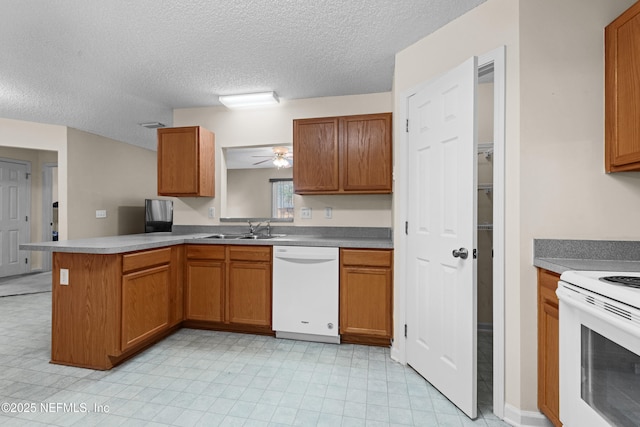 kitchen featuring white appliances, brown cabinets, a peninsula, a textured ceiling, and a sink