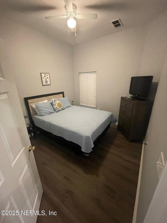 bedroom featuring visible vents, ceiling fan, a textured ceiling, and wood finished floors