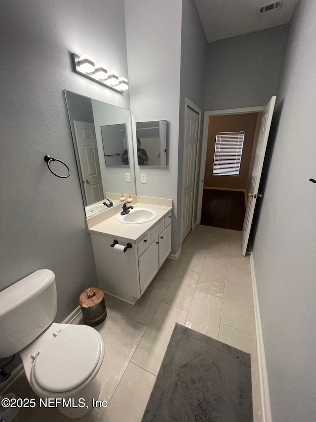 bathroom featuring toilet, visible vents, vanity, and baseboards