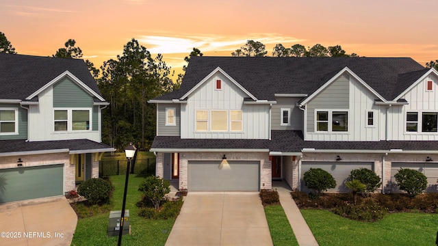 townhome / multi-family property with a garage, driveway, board and batten siding, and a front yard