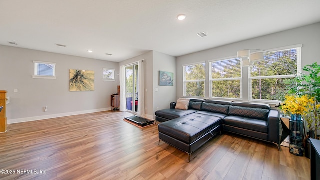 living room featuring light wood-style floors, visible vents, and baseboards