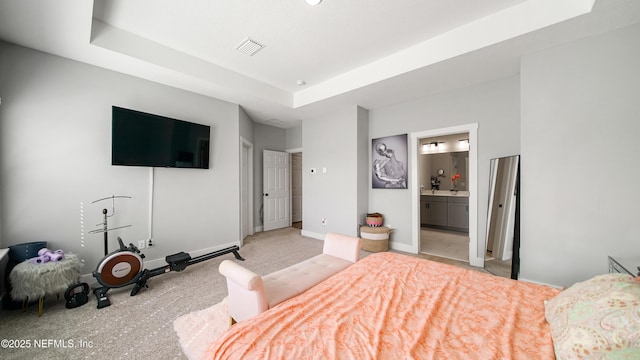 bedroom with baseboards, visible vents, a raised ceiling, and ensuite bathroom