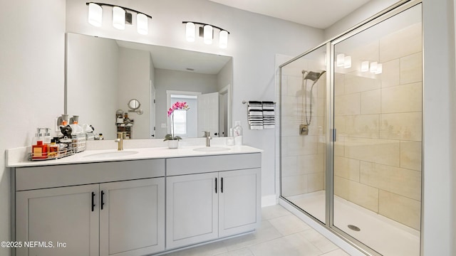 full bath featuring double vanity, a stall shower, tile patterned flooring, and a sink