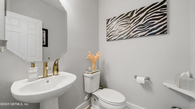 bathroom featuring a sink, toilet, and baseboards