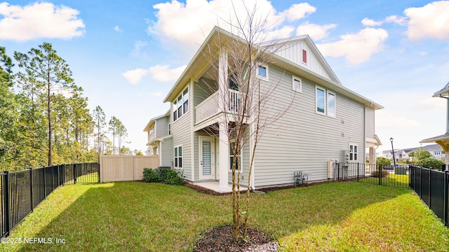 rear view of house featuring a yard, board and batten siding, a fenced backyard, and a balcony