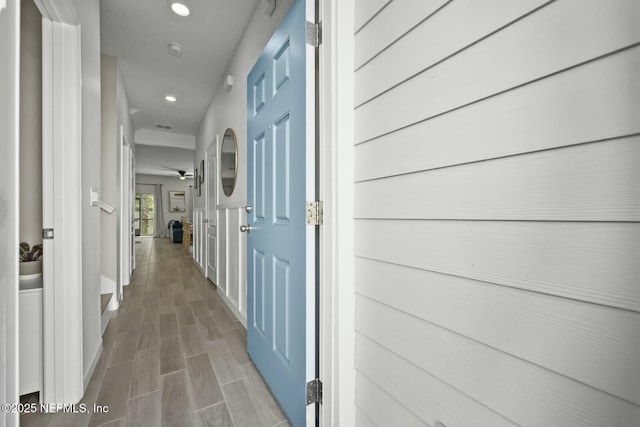 hall featuring wood tiled floor, visible vents, baseboards, and recessed lighting